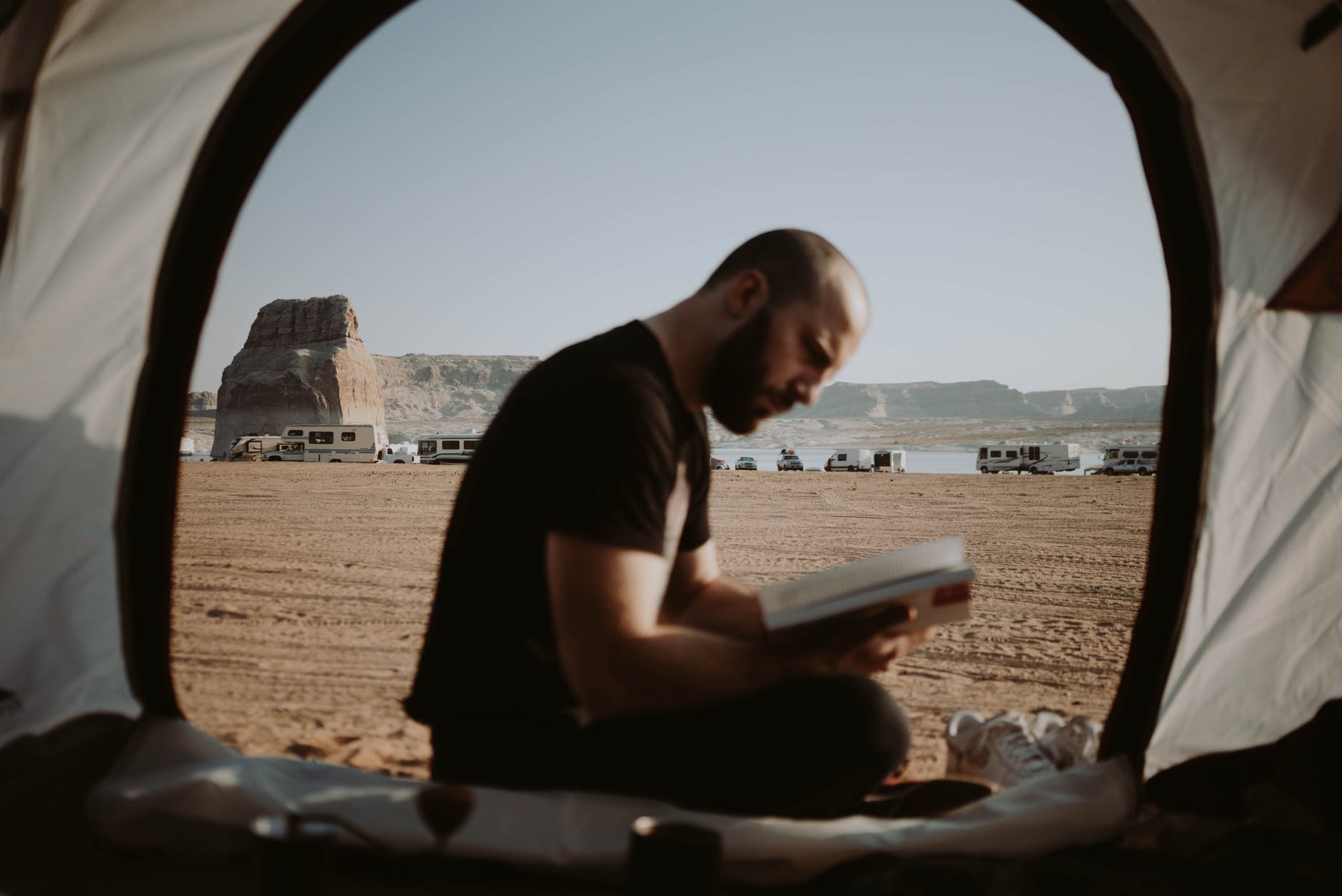 man reading book in tent